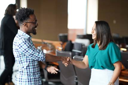 Man and woman shaking hands and smiling in a conference room 